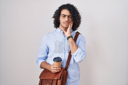 Photo for Hispanic man with curly hair drinking a cup of take away coffee touching mouth with hand with painful expression because of toothache or dental illness on teeth. dentist concept. - Royalty Free Image