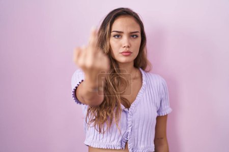 Foto de Young hispanic woman standing over pink background showing middle finger, impolite and rude fuck off expression - Imagen libre de derechos