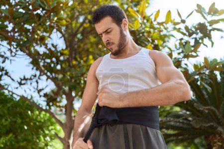 Téléchargez les photos : Jeune homme hispanique karaté combattant attacher ceinture au parc - en image libre de droit