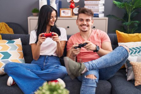 Foto de Hombre y mujer pareja jugando videojuego sentado en el sofá en casa - Imagen libre de derechos