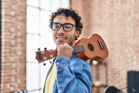 Téléchargez les photos : Jeune musicien hispanique tenant ukulele au studio de musique - en image libre de droit