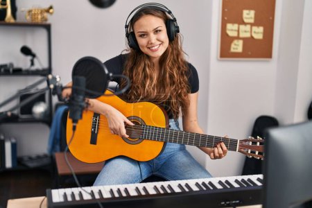 Photo for Young beautiful hispanic woman musician playing classical guitar at music studio - Royalty Free Image