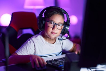 Photo for Adorable hispanic boy streamer smiling confident sitting on table at gaming room - Royalty Free Image