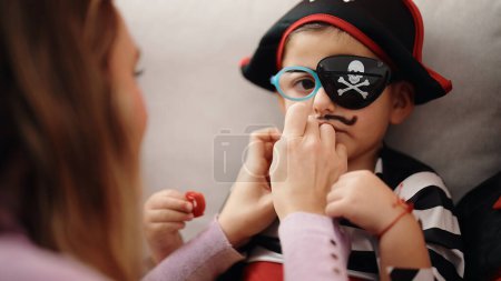 Foto de Adorable niño hispano con traje de pirata recibiendo sorteo de bigote en casa - Imagen libre de derechos