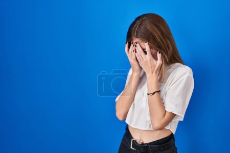 Photo for Beautiful woman standing over blue background with sad expression covering face with hands while crying. depression concept. - Royalty Free Image