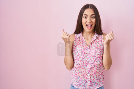 Photo for Young hispanic woman with long hair standing over pink background celebrating surprised and amazed for success with arms raised and open eyes. winner concept. - Royalty Free Image