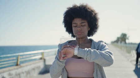 Photo for African american woman using stopwatch standing at seaside - Royalty Free Image