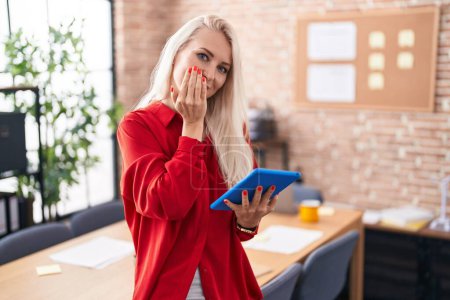 Photo for Caucasian woman working at the office with tablet laughing and embarrassed giggle covering mouth with hands, gossip and scandal concept - Royalty Free Image