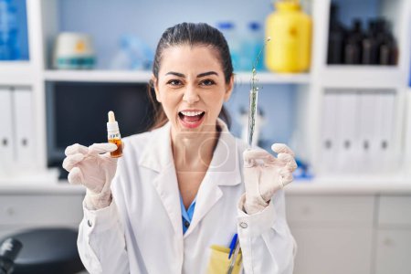 Photo for Young woman doing weed oil extraction at laboratory angry and mad screaming frustrated and furious, shouting with anger. rage and aggressive concept. - Royalty Free Image