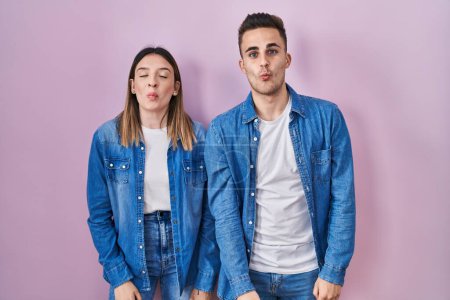 Photo for Young hispanic couple standing over pink background making fish face with lips, crazy and comical gesture. funny expression. - Royalty Free Image