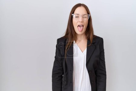 Téléchargez les photos : Belle femme brune portant une veste d'affaires et des lunettes collant la langue heureuse avec une expression drôle. concept d'émotion. - en image libre de droit