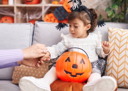 Photo for Adorable hispanic girl wearing halloween costume drawing on hand at home - Royalty Free Image