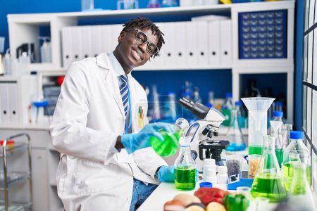 Foto de Hombre científico afroamericano vertiendo líquido en tubo de ensayo en laboratorio - Imagen libre de derechos
