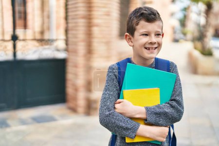 Photo for Blond child student holding books standing at street - Royalty Free Image