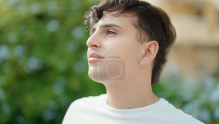 Téléchargez les photos : Homme non binaire regardant vers le côté avec une expression sérieuse au parc - en image libre de droit