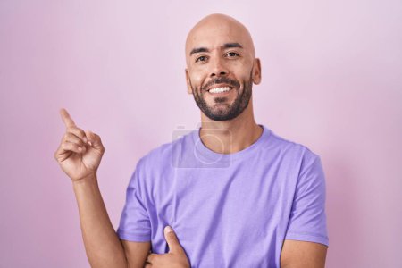 Téléchargez les photos : Moyen Age chauve homme debout sur fond rose souriant heureux pointant avec la main et le doigt sur le côté - en image libre de droit