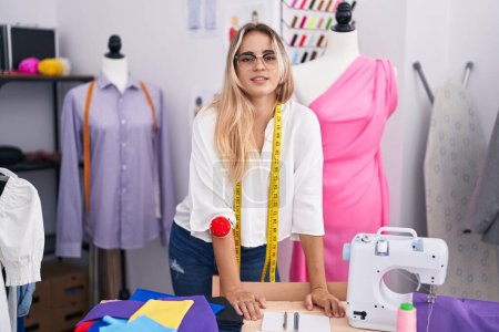 Téléchargez les photos : Jeune femme blonde tailleur souriant confiance debout au magasin de vêtements - en image libre de droit