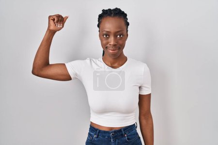 Foto de Hermosa mujer negra de pie sobre el fondo aislado persona fuerte que muestra el músculo del brazo, confiado y orgulloso de poder - Imagen libre de derechos