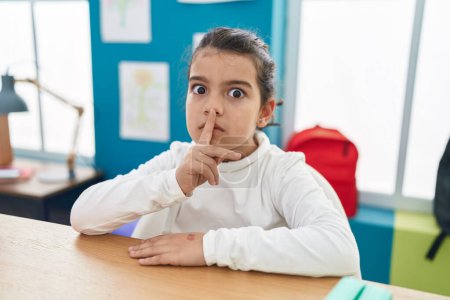 Photo for Adorable hispanic girl student asking for silence at classroom - Royalty Free Image