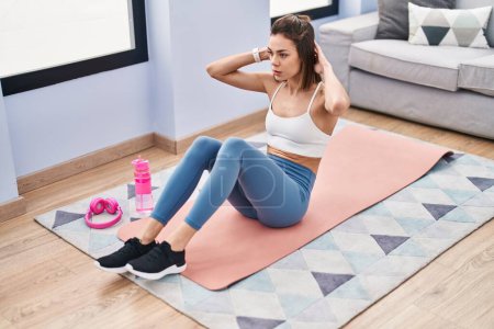 Photo for Young beautiful hispanic woman training abs exercise at home - Royalty Free Image