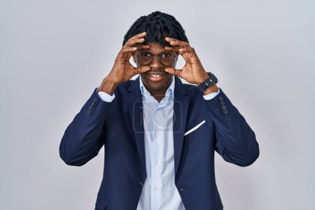 Foto de Hombre africano joven con rastas con chaqueta de negocios sobre fondo blanco tratando de abrir los ojos con los dedos, soñoliento y cansado para la fatiga de la mañana - Imagen libre de derechos
