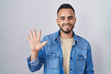 Téléchargez les photos : Jeune homme hispanique debout sur fond isolé montrant et pointant vers le haut avec les doigts numéro cinq tout en souriant confiant et heureux. - en image libre de droit