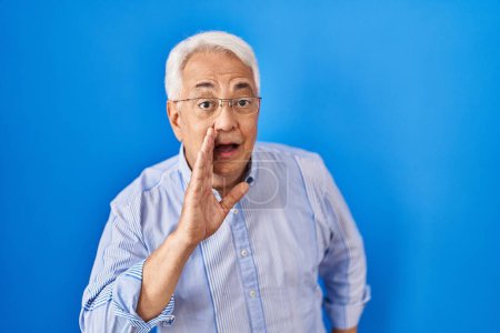 Téléchargez les photos : Hispanique senior homme portant des lunettes main sur bouche dire rumeur secrète, chuchotant conversation malicieuse - en image libre de droit