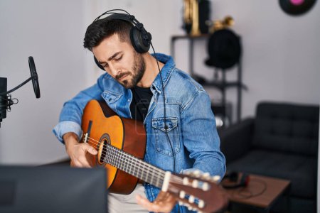 Téléchargez les photos : Jeune homme hispanique jouant de la guitare classique au studio de musique - en image libre de droit