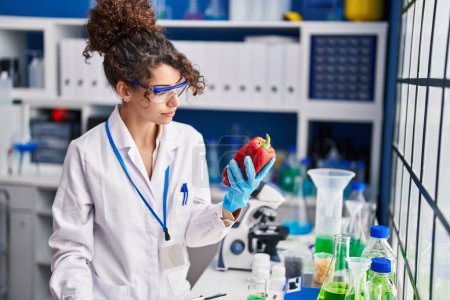 Photo for Young hispanic woman scientist analysing red pepper at laboratory - Royalty Free Image