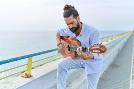 Photo for Young hispanic man musician playing classical guitar at seaside - Royalty Free Image