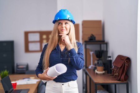 Photo for Young woman wearing architect hardhat serious face thinking about question with hand on chin, thoughtful about confusing idea - Royalty Free Image