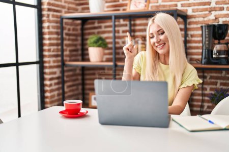 Photo for Caucasian woman doing video call with laptop smiling happy pointing with hand and finger to the side - Royalty Free Image