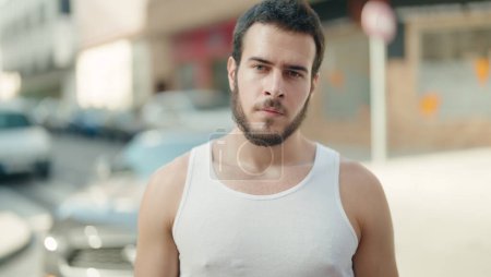 Téléchargez les photos : Jeune homme hispanique regardant vers le côté avec une expression sérieuse dans la rue - en image libre de droit