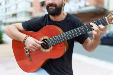 Foto de Young hispanic man musician playing classical guitar at street - Imagen libre de derechos