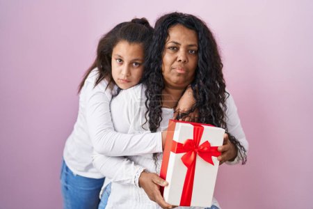 Photo for Mother and young daughter holding with presents relaxed with serious expression on face. simple and natural looking at the camera. - Royalty Free Image