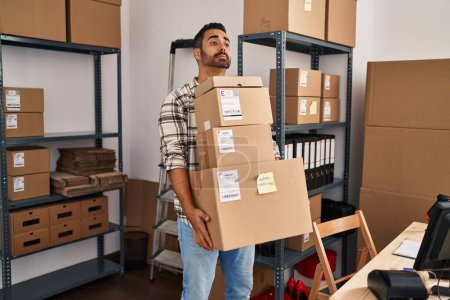 Téléchargez les photos : Jeune homme hispanique ecommerce business worker holding packages at office - en image libre de droit