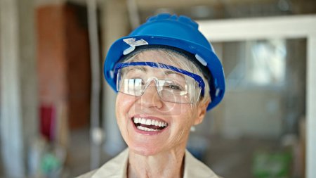 Téléchargez les photos : Moyen Age femme blonde architecte souriant confiance debout sur le chantier de construction - en image libre de droit