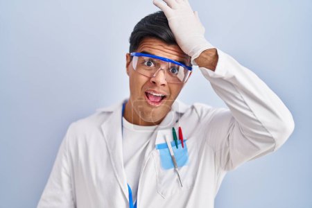 Photo for Hispanic man working as scientist surprised with hand on head for mistake, remember error. forgot, bad memory concept. - Royalty Free Image