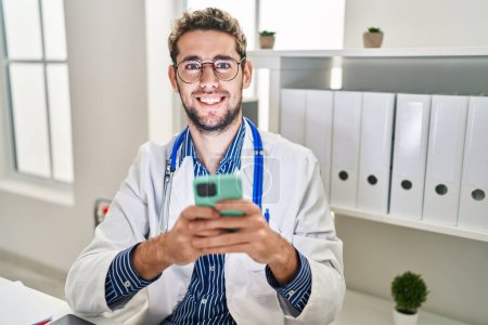 Photo for Young man doctor using smartphone working at clinic - Royalty Free Image