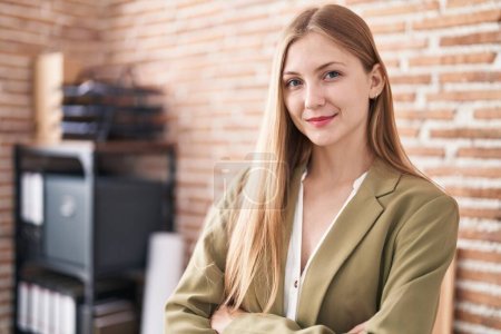 Young caucasian woman business worker standing with arms crossed gesture at office-stock-photo