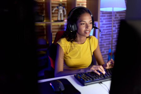 Photo for Young african american woman streamer playing video game using computer at gaming room - Royalty Free Image