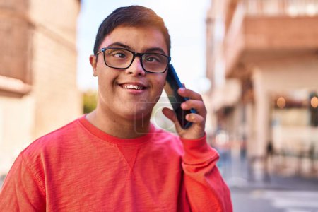 Foto de Síndrome de Down hombre sonriendo confiado hablando en el teléfono inteligente en la calle - Imagen libre de derechos