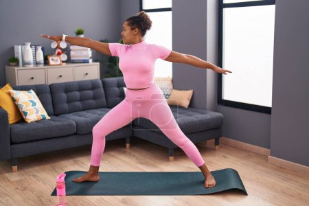 Foto de Mujer afroamericana sonriendo segura de entrenar yoga en casa - Imagen libre de derechos