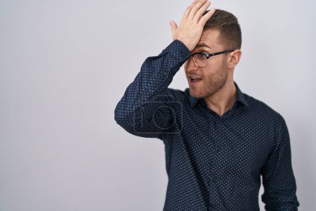 Photo for Young caucasian man standing over isolated background surprised with hand on head for mistake, remember error. forgot, bad memory concept. - Royalty Free Image