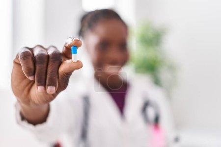 Téléchargez les photos : Femme afro-américaine portant un uniforme de médecin tenant la pilule à la clinique - en image libre de droit