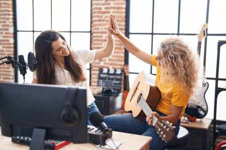 Photo for Two women musicians high five with hands raised up at music studio - Royalty Free Image