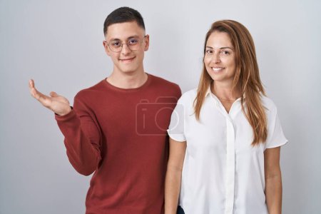 Photo for Mother and son standing together over isolated background smiling cheerful presenting and pointing with palm of hand looking at the camera. - Royalty Free Image