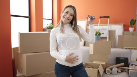 Téléchargez les photos : Jeune femme enceinte touchant le ventre tenant des clés à la nouvelle maison - en image libre de droit