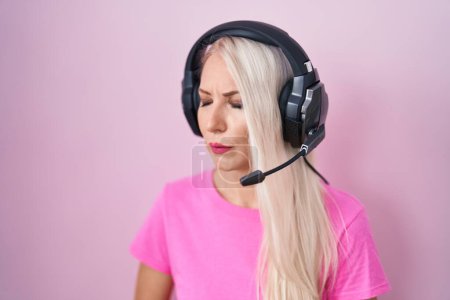 Photo for Caucasian woman listening to music using headphones with hand on stomach because nausea, painful disease feeling unwell. ache concept. - Royalty Free Image