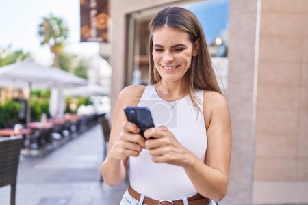 Photo for Young beautiful hispanic woman smiling confident using smartphone at coffee shop terrace - Royalty Free Image
